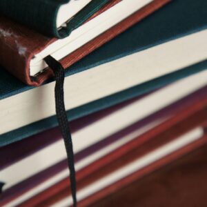 A detailed view of a stack of colorful hardcover books with visible bookmarks.