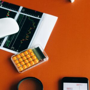 Desk setup with calculator, graphs, and tools on orange surface for financial analysis.